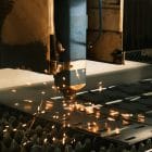 A machine cutting a piece of metal with sparks